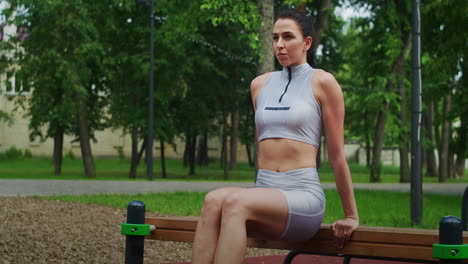 A-female-athlete-performs-reverse-exercises-on-a-bench-in-a-Park-in-slow-motion.-Beautiful-woman-playing-sports-in-the-Park
